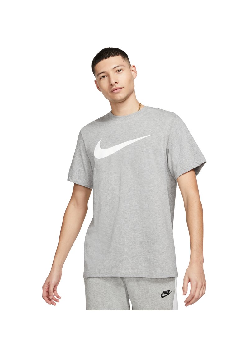 Grå bomulds T-shirt med et stort hvidt Nike swoosh-logo. Korte ærmer, rund hals, afslappet pasform, glat tekstur.
