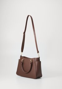 Sac à main synthétique marron au design structuré, avec deux poignées et une bandoulière réglable. Comprend des accessoires en métal doré et des poches latérales.