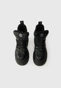 Mustad mustad faux karusnaha voodriga, pehmendatud krae, nööridega disain ja tekstureeritud kummist tald. Buffalo brändimisnimega külgedel ja ümar silt peal.