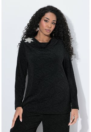 Haut noir à manches longues avec un motif subtil de feuilles, un col bénitier et une broche argentée en forme de fleur sur l'épaule gauche.