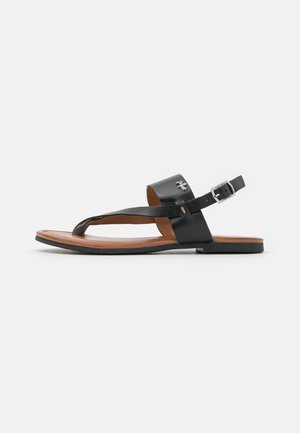 Sort læder flad sandal med forrest tå-loop, ankelrem med sølvspænde og brun indersål.