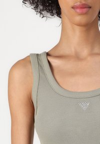 Kergelt roheline ilma varrukateta ribiga tank top ümmarguse kaelusega. Keskel on väike rhinestone'idega kolmnurk. Pehme tekstuur.