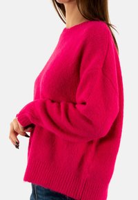 Maglione lavorato a maglia fucsia con maniche lunghe, orlo a coste e vestibilità comoda. Tessuto morbido con una silhouette leggermente oversize.