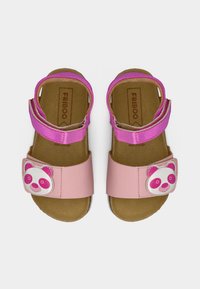 Παιδικά ροζ σανδάλια με ανοιχτά δάχτυλα, ρυθμιζόμενα λουράκια και διακοσμήσεις με πρόσωπο πάντα στα μπροστινά λουράκια, απεικονιζόμενα από πάνω.