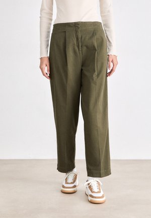 Pantaloni a gamba larga verde oliva realizzati in un tessuto liscio, con vita alta, pieghe e una vestibilità rilassata. Abbinati a sneakers bianche e marroni.
