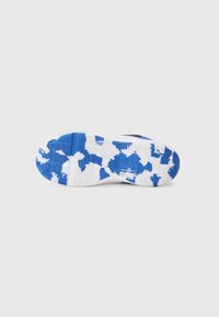 Semelle de chaussure avec une base blanche ornée de motifs camouflés bleus, texturée avec des rainures pour l'adhérence. Le matériau semble en caoutchouc et flexible.
