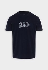 Námořnická modrá bavlněná tričko s bílým obloukovým nápisem "GAP" přes hrudník. Krátké rukávy, kulatý výstřih a měkká textura.