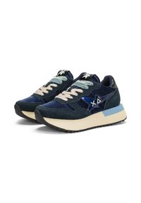 Un paio di sneaker in suede blu navy con suole crema e azzurro chiaro, lacci beige e un emblema a forma di stella lucido sui lati.