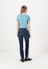 Světle modré tričko s krátkým rukávem v kombinaci s tmavě modrými skinny džínami. Džíny mají klasický design s pěti kapsami a hladký povrch.