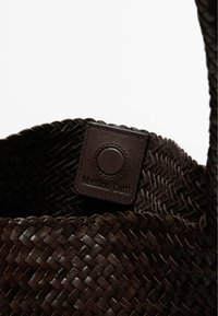 Woven dark brown leather bag featuring a textured surface and a rectangular tag embossed with "Massimo Dutti." Open-top design.