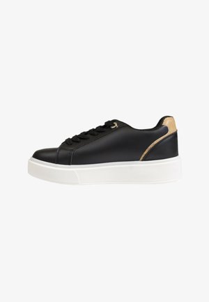 Sneaker in ecopelle nera con suola in gomma bianca, punta rotonda, chiusura con lacci, dettagli dorati e un accento marrone chiaro sul tallone.