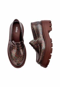 Błyszczące czarne mokasyny z tęczowymi iskierkami, z grubą brązową podeszwą. Gładka tekstura, z łatwym w zakładaniu designem i zaokrąglonymi krawędziami.