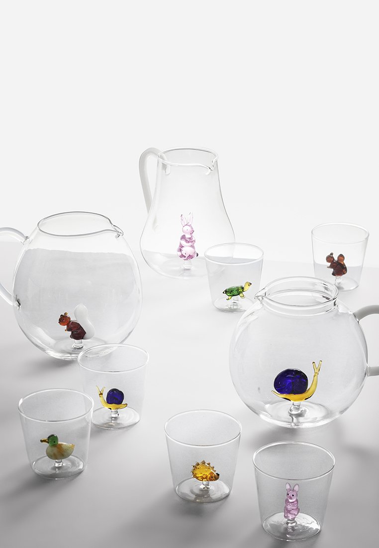 Szklane czajniki i filiżanki z kolorowymi figurkami zwierząt w środku, w tym ślimakiem, kaczuszką, żółwiem i królikiem; przezroczyste, gładkie i błyszczące powierzchnie.