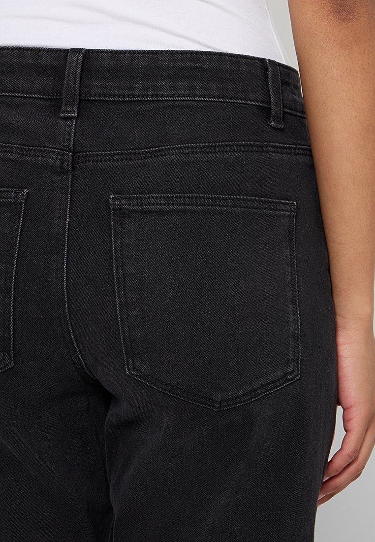 Schwarze Jeans aus Denim mit einer figurbetonten Passform, zwei Gesäßtaschen und einer sichtbaren Naht entlang des Bundes und der Taschen.