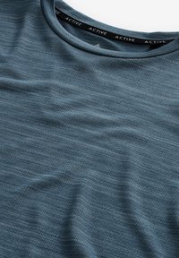 Camiseta de deporte en azul oscuro, hecha de un tejido texturizado con sutiles rayas horizontales y un escote redondo que presenta una etiqueta negra con la palabra "ACTIVE".
