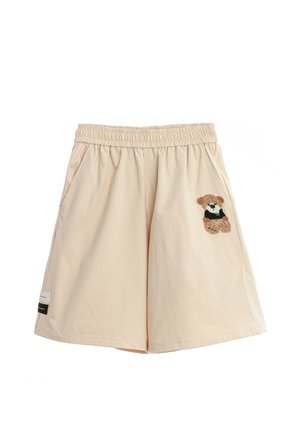 Pantalones cortos beige con cintura elástica y bolsillos laterales, decorados con un pequeño oso de peluche bordado en el lado derecho y dos etiquetas de tela cerca del dobladillo izquierdo.