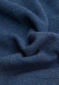 Granatowy materiał z teksturowanym splotem, charakteryzujący się subtelnymi różnicami w przędzy. Tkanina wydaje się miękka i nieco elastyczna.