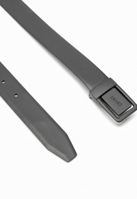 Cintura in pelle grigia con una fibbia rettangolare in metallo nero. La cintura è liscia, con un'estremità appuntita e presenta sette fori di regolazione.