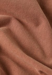 Un tessuto con una trama morbida e testurizzata, caratterizzato da un caldo colore rosa tenue. Il tessuto presenta lievi variazioni di tonalità e motivo.