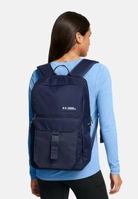 Mochila azul marino hecha de un tejido resistente, con múltiples compartimentos, correas ajustables y un cierre de hebilla en la parte frontal para un almacenamiento seguro.