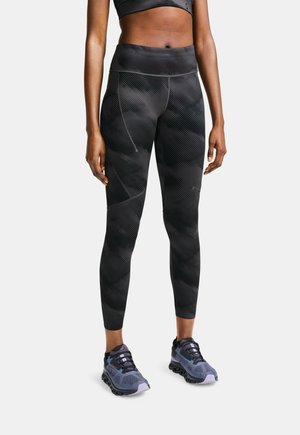 Black high-waisted leggings with textured diagonal stripes, paired with gray athletic shoes featuring purple accents and a cushioned sole.
