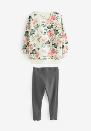 Cvečni pulover v kremni barvi s pinki in zelenimi cvetovi, v kombinaciji s sivimi rebrastimi pajkicami. Ima dolge rokave in okrogel ovratnik.