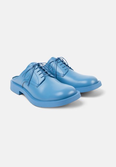 Scarpe blu in pelle senza lacci, con punta arrotondata e finitura liscia. Presentano una suola in gomma blu solida e dettagli di cucitura minimi.