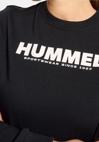 Sudadera negra con cuello acanalado y mangas largas. En el frente muestra un texto blanco en negrita: "HUMMED SPORTSWEAR SINCE 1923."