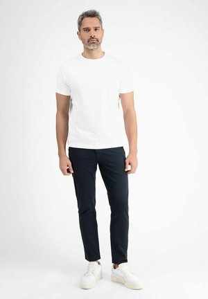 Weißes T-Shirt mit kurzen Ärmeln, marineblaue Slim-Fit-Hose und weiße Sneaker. Sauberes Design, weiche Textur und kräftige Farben. Keine Muster oder Akzente.