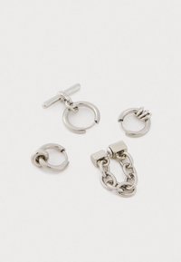 Τέσσερα ασημένια μεταλλικά σκουλαρίκια με σχέδια σε σχήμα κύκλου, αλυσίδας και ράβδου σε λευκό φόντο.