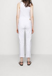 Bílé denimové džíny se středním pasem a přímým střihem nohavic, s dvěma zadními kapsami a malou texturovanou etiketou na pasu.