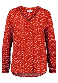 Blouse rouge à manches longues avec un col en V et un motif de cœurs blancs, fabriquée en tissu l�éger avec une coupe décontractée et un ourlet arrondi.