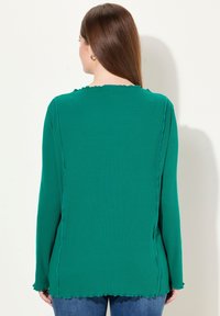 Groene top met lange mouwen, een scalloped halslijn en een getextureerde afwerking, met rechte naden en een ronde zoom.