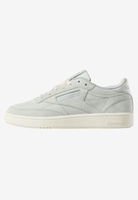 Baskets Reebok en daim gris clair avec semelle en caoutchouc blanche et lacets, coutures visibles, et logo Reebok sur le côté et le talon.