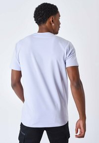 Camiseta de algodón de un suave color púrpura claro, con mangas cortas, un escote redondo y una textura lisa. La parte trasera presenta un diseño sencillo sin logotipos.