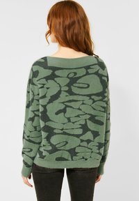 Zielony sweter z teksturowanym kwiatowym wzorem, szerokim dekoltem i luźnym krojem. Długie rękawy z prążkowanymi mankietami, miękki materiał i swobodny design.