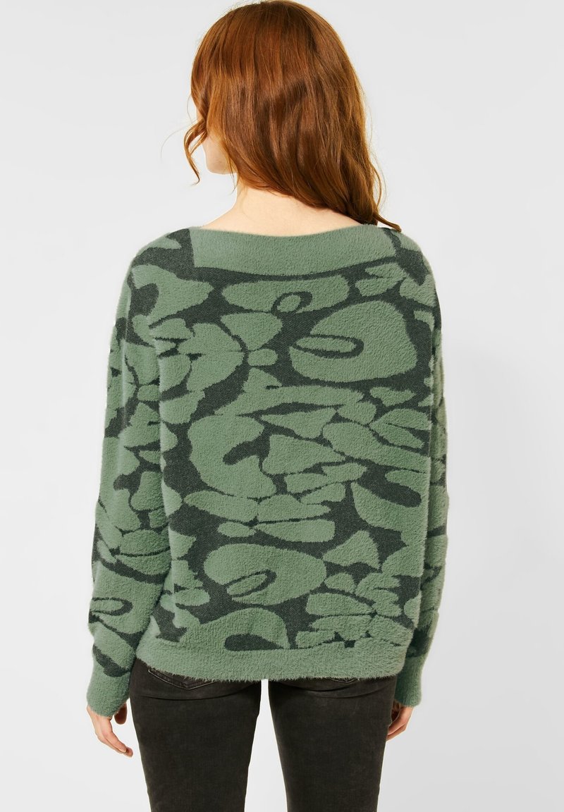 Zielony sweter z teksturowanym kwiatowym wzorem, szerokim dekoltem i luźnym krojem. Długie rękawy z prążkowanymi mankietami, miękki materiał i swobodny design.