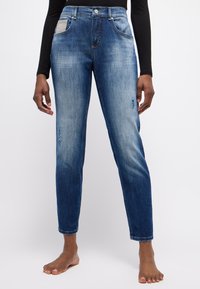 Dunkelblaue Denim-Jeans mit geradem Bein, die an den Oberschenkeln eine hellere Waschung und verwaschene Details aufweisen. Enthält eine strukturierte Tasche.