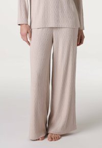 Set di abbigliamento da casa in maglia beige chiaro, composto da pantaloni a gamba larga e una maglietta a maniche lunghe con un motivo a treccia. Tessuto morbido e dalla consistenza particolare.