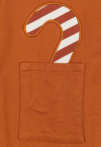 Oranje stof heeft een klepzak met een gestreept zuurstokontwerp in rood en wit, omlijnd met gele stiksels.