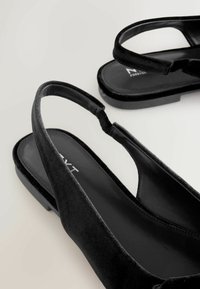 Melnas zamšādas slingback baleta kurpes ar gludu zoli, atvērtu purngali un minimālistisku dizainu, kas aprīkotas ar mīkstu siksniņu vieglai uzvilkšanai.