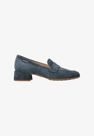 Mocassin pour femme en daim gris foncé à petit talon, bout arrondi et semelle en caoutchouc marron, étiquette latérale visible.