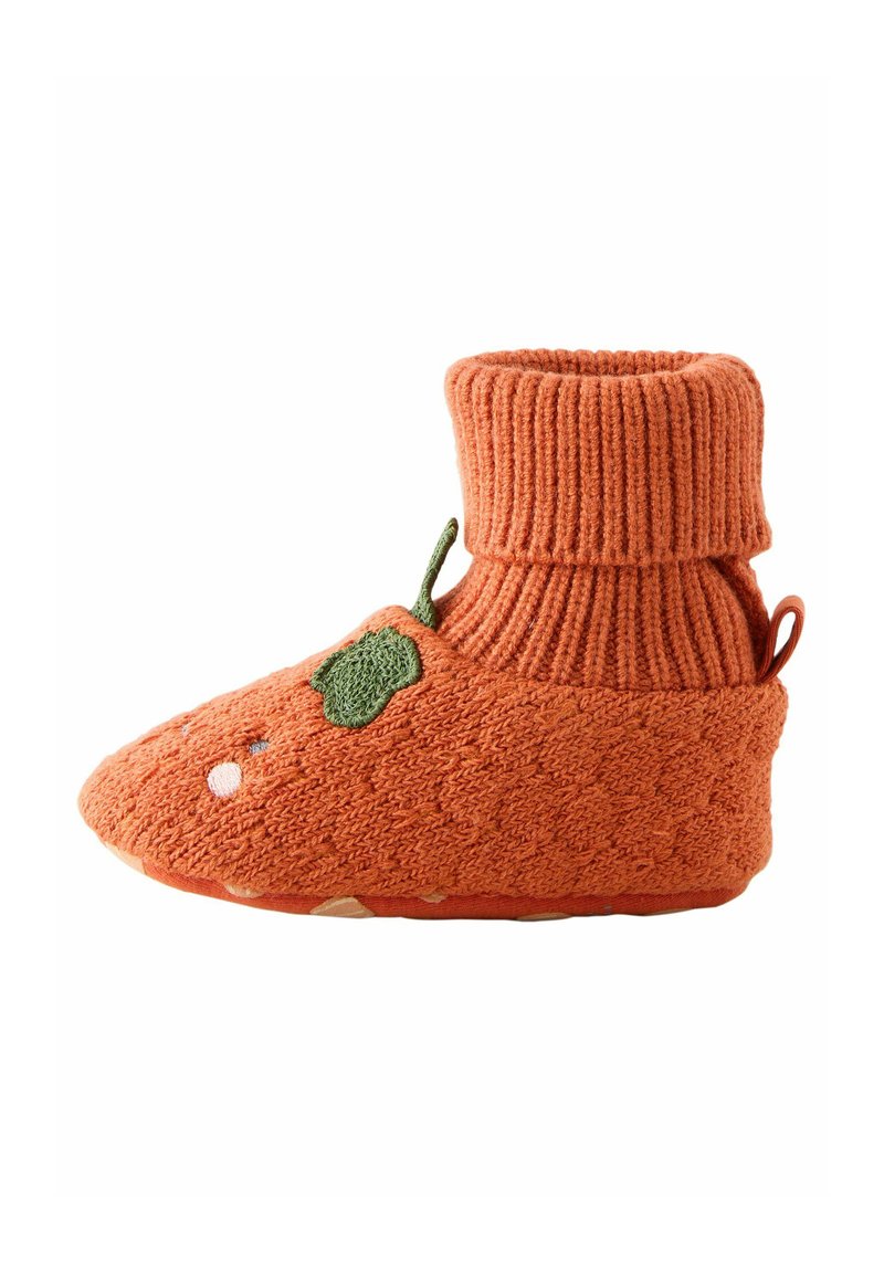 Chaussons tricotés orange avec un ourlet côtelé et un accent de feuille verte. La semelle est texturée avec un motif de grip subtil pour la traction.