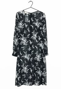 Robe noire en tissu transparent ornée de motifs floraux blancs. Manches longues, encolure ronde et fermeture à boutons au dos.