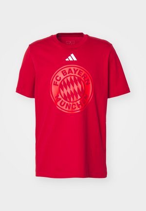Red cotton t-shirt featuring a large circular FC Bayern München logo in the center. Adidas three-stripe logo on the upper right.