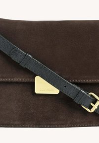 Sac à main en daim marron avec une bandoulière en cuir texturé noir et des accessoires en métal doré. Il dispose d'une fermeture à fermoir et d'un accent logo rectangulaire.