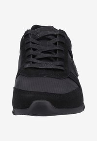 Černá sportovní obuv s kombinací hladkých a strukturovaných materiálů, šněrováním, polstrovaným límcem a gumovou podešví.
