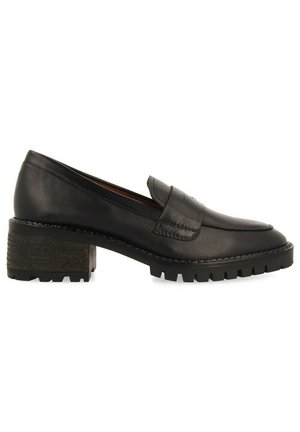 Mocassins en cuir noir avec un talon texturé épais, présentant un bout arrondi et de subtils détails de couture sur la tige.