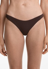 Tmavě hnědé bikini kalhotky s minimalistickým designem, s nízkým střihem a jemnou texturou, vhodné na plavání nebo na pláž.
