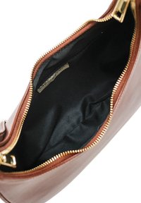 Sac à main en cuir marron avec fermeture éclair ; l'intérieur doublé présente une petite poche et un tissu noir doux, mettant en valeur des accessoires en acier inoxydable doré.